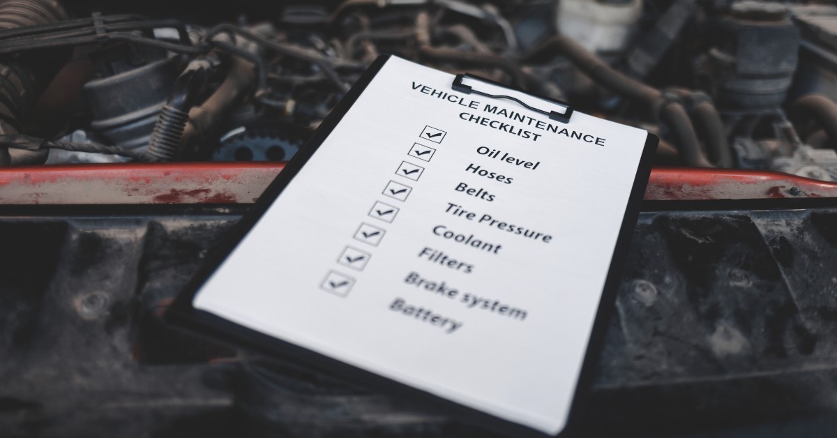 Vehicle Maintenance Checklist on Clipboard Above The Engine of a Vehicle | How To Maintain Your Vehicle This Summer | Sierra Blanca Motors