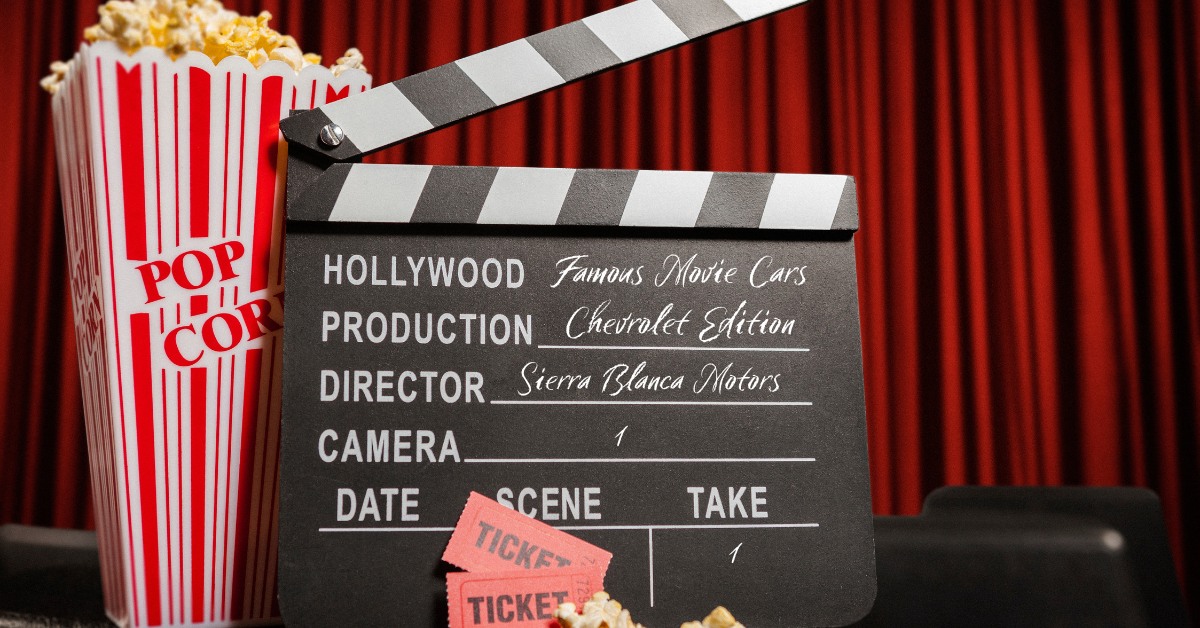 Red Stage Curtains in the Background with A Red and White Popcorn Bucket Next to a Clapperboard | Famous Chevrolet Vehicles in Movies | Sierra Blanca Motors