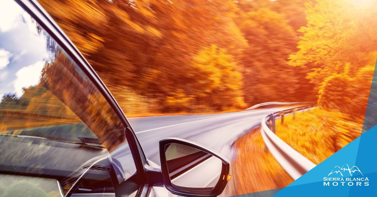 Car driving through fall weather. Sierra Blanca Motors. Fall vehicle check-ups.